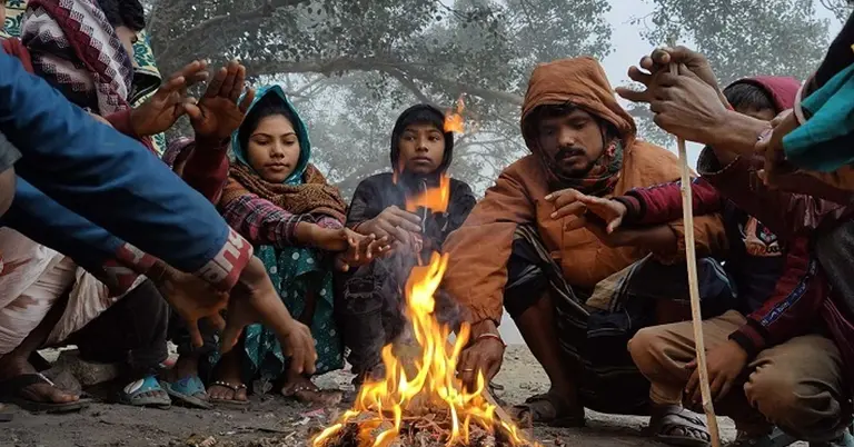 শীতের সকালে আগুনে তাপ নিচ্ছেন
