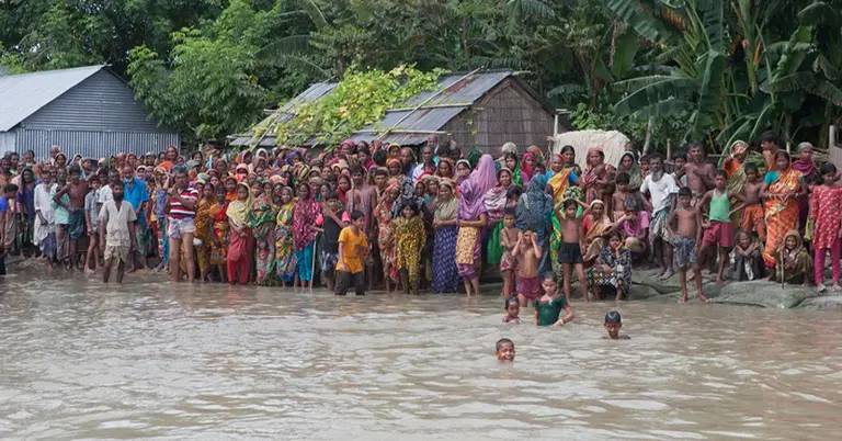 ২০১৬ সালের জুলাই মাসে বন্যা থেকে বাঁচতে নৌকার জন্য অপেক্ষা করছেন বাংলাদেশের গ্রামবাসীরা।